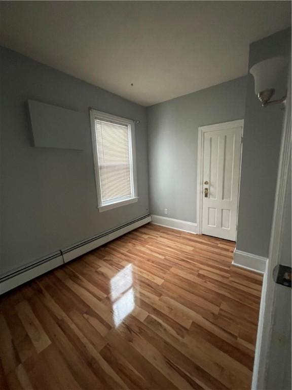 unfurnished bedroom featuring a baseboard radiator, wood finished floors, and baseboards