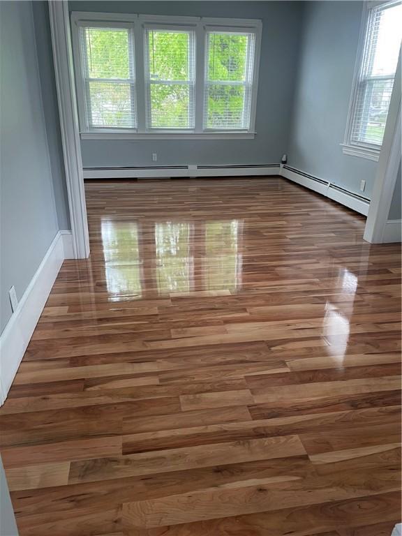 spare room featuring a baseboard heating unit and wood finished floors