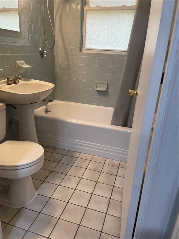 bathroom featuring shower / bath combo, tile patterned flooring, toilet, and tile walls