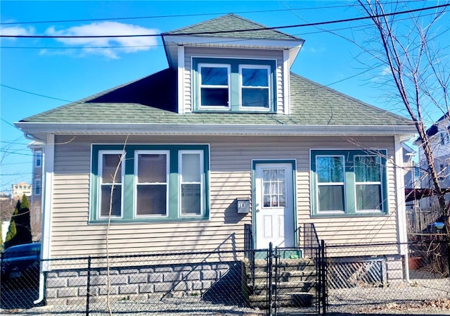 view of front facade with a fenced front yard and a shingled roof