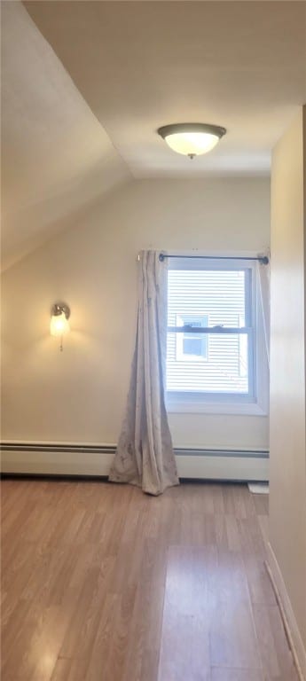 corridor with lofted ceiling, baseboards, a baseboard heating unit, and wood finished floors