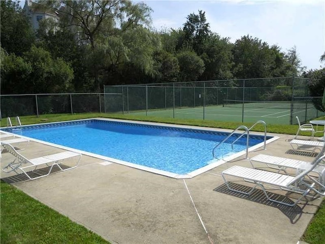 view of swimming pool with a tennis court, a patio area, fence, and a fenced in pool