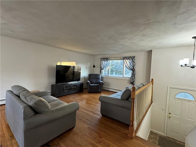 living room with a textured ceiling, wood finished floors, a baseboard radiator, and a chandelier