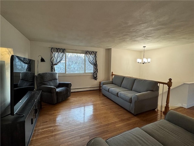 living area with hardwood / wood-style floors, a textured ceiling, baseboard heating, and a chandelier