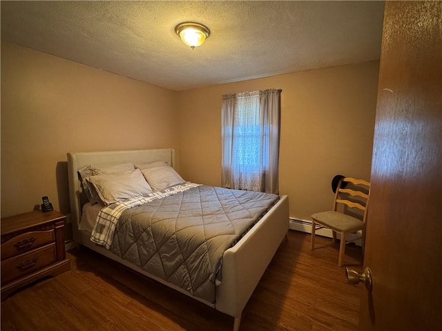 bedroom with dark wood-style floors, baseboard heating, and a textured ceiling