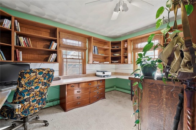 office area featuring light colored carpet, baseboard heating, a ceiling fan, and built in study area