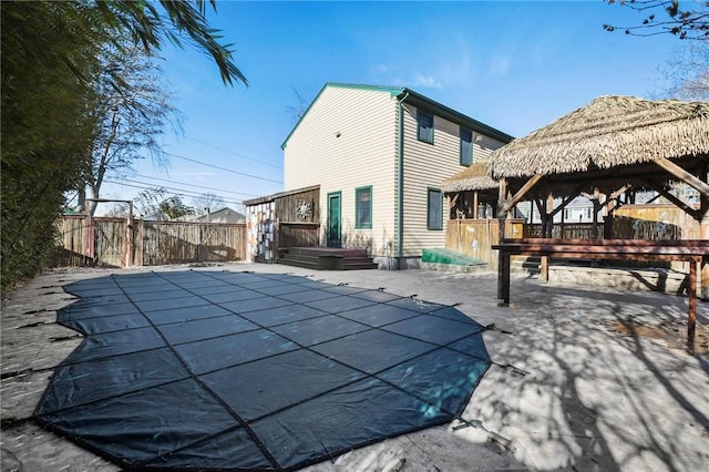 rear view of property featuring fence, a fenced in pool, a gazebo, a deck, and a patio area