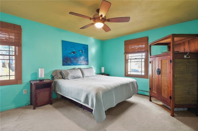 bedroom featuring light carpet, a baseboard heating unit, and a ceiling fan