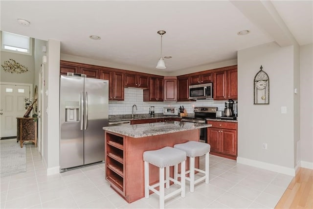 kitchen with decorative backsplash, a breakfast bar area, appliances with stainless steel finishes, and a kitchen island