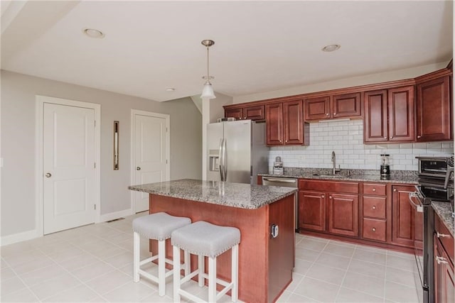 kitchen featuring a kitchen bar, a sink, a kitchen island, appliances with stainless steel finishes, and decorative backsplash