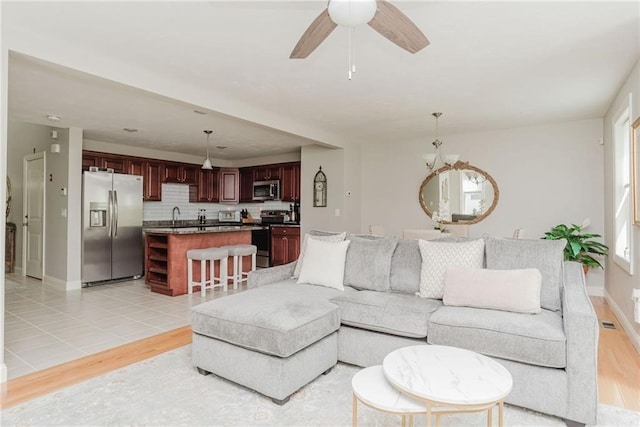 living room with baseboards, light wood-type flooring, and a ceiling fan