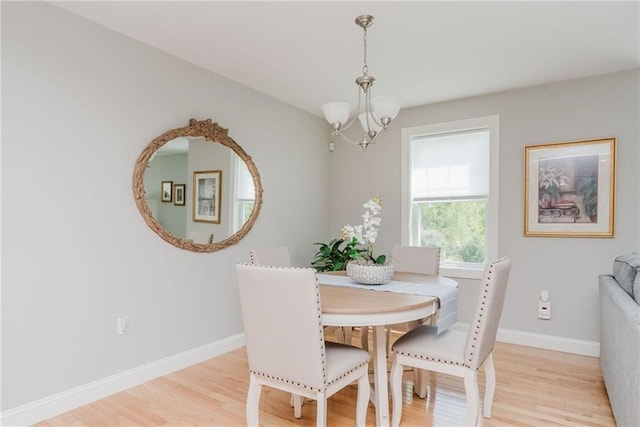 dining area featuring baseboards, light wood-style floors, and an inviting chandelier