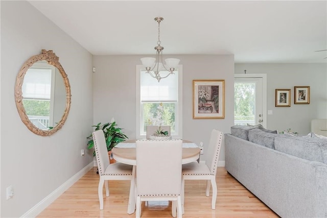 dining room featuring baseboards, light wood-style floors, and a chandelier