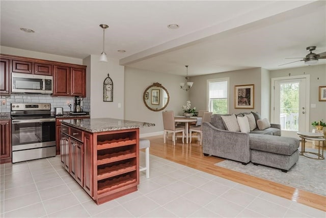 kitchen featuring open shelves, open floor plan, appliances with stainless steel finishes, decorative backsplash, and dark brown cabinets