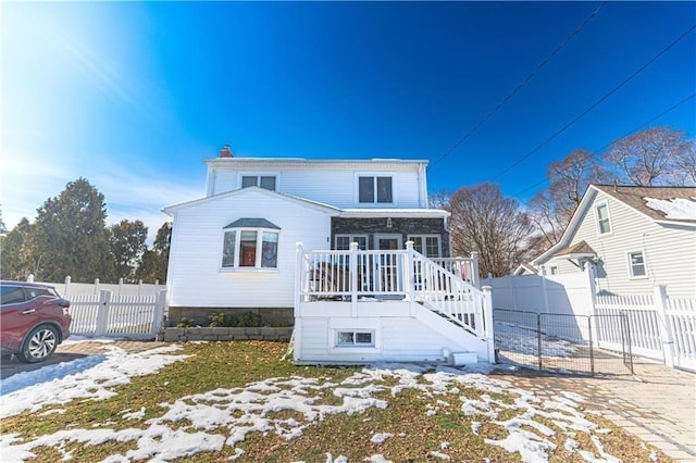 view of front of home with stairs, a chimney, and fence