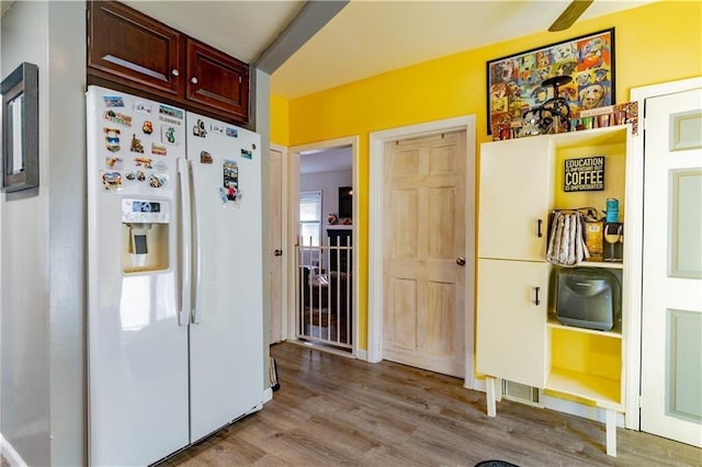 kitchen with light wood-style flooring, white refrigerator with ice dispenser, and reddish brown cabinets