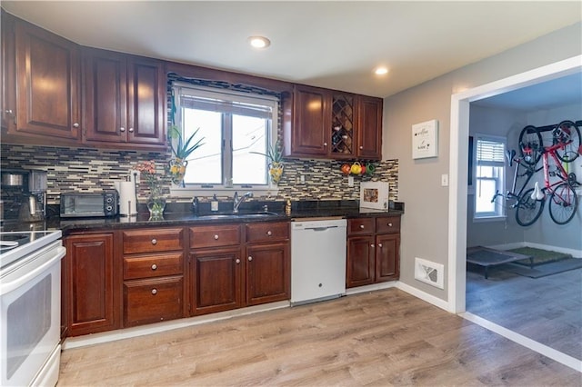 kitchen featuring light wood finished floors, white appliances, a wealth of natural light, and a sink