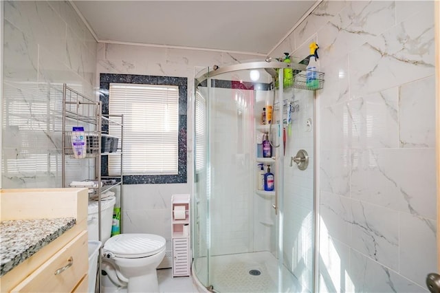 bathroom with a shower stall, tile walls, vanity, and toilet