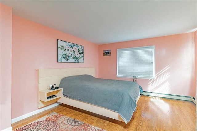 bedroom featuring light wood-type flooring, a baseboard heating unit, and baseboards