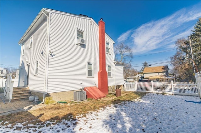 exterior space with cooling unit, a chimney, and fence