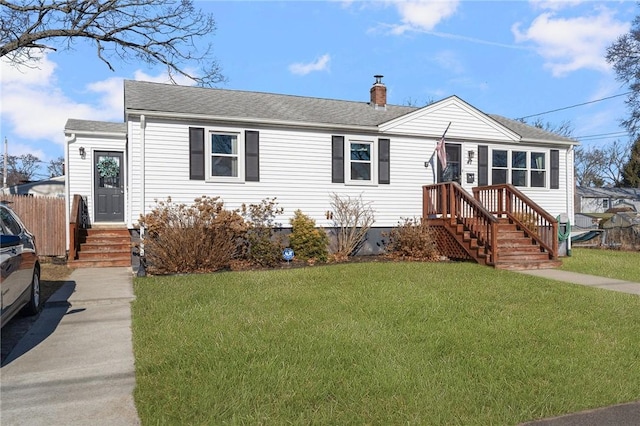 view of front of property featuring a chimney, roof with shingles, a front yard, and fence