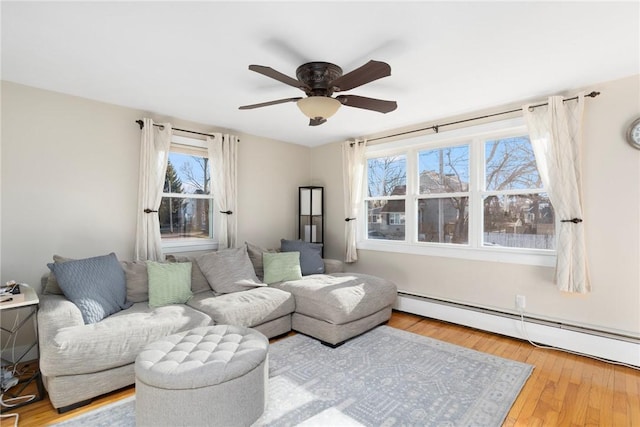 living room with baseboard heating, a ceiling fan, and hardwood / wood-style floors