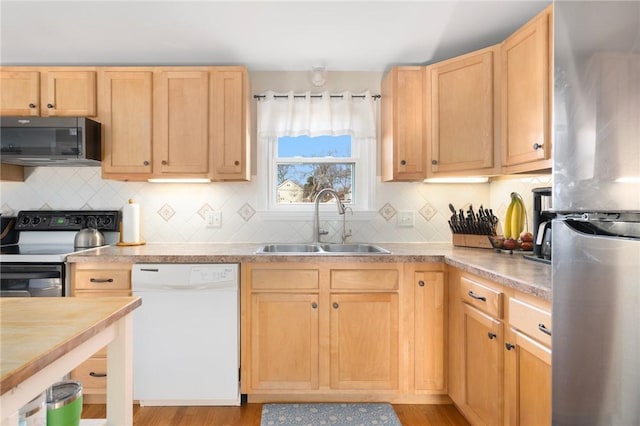 kitchen featuring light brown cabinets, backsplash, appliances with stainless steel finishes, and a sink