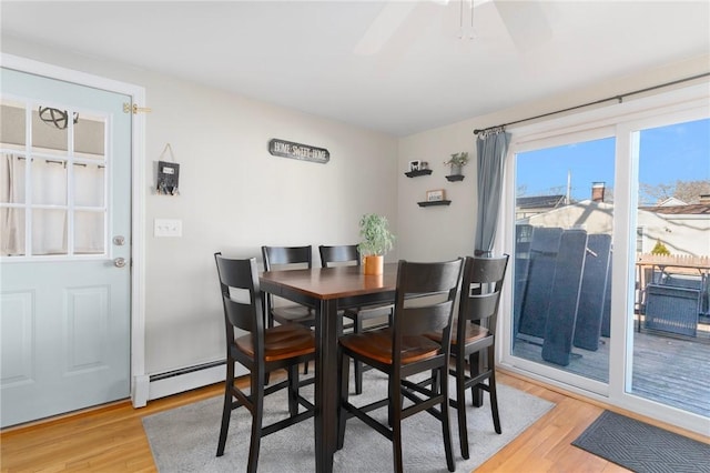 dining area with a baseboard radiator, light wood-style floors, and a ceiling fan