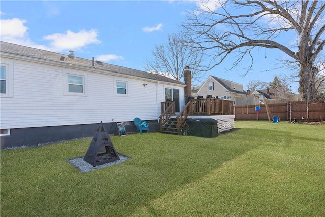 back of property with a wooden deck, a yard, and fence