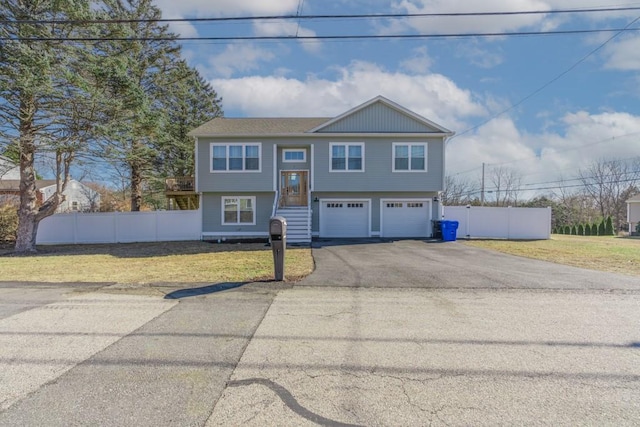 split foyer home featuring a garage, a front yard, driveway, and fence