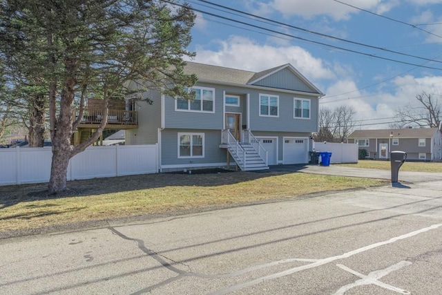 split foyer home with a garage, concrete driveway, a front lawn, and fence