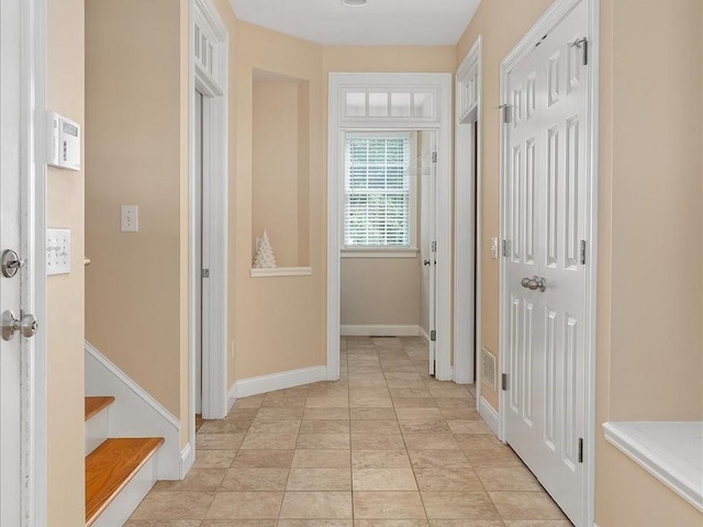 hall with light tile patterned floors, stairway, and baseboards