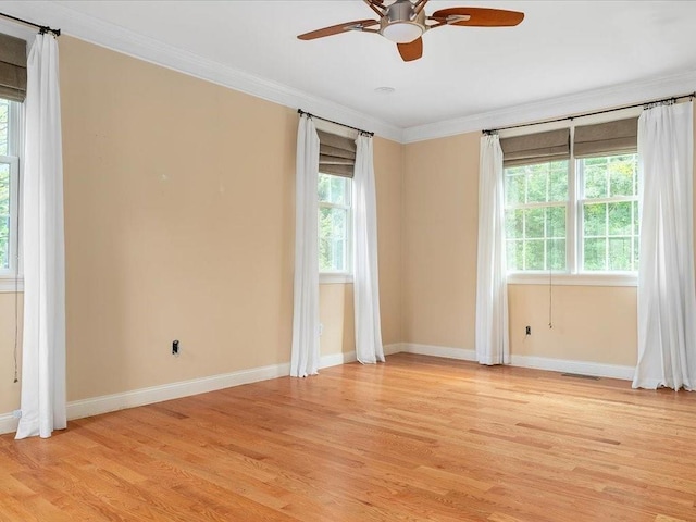 spare room featuring light wood-type flooring, baseboards, visible vents, and crown molding