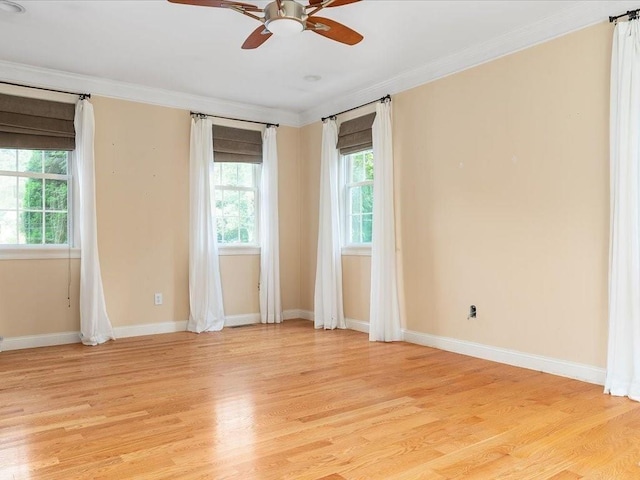 spare room with a wealth of natural light, light wood-type flooring, baseboards, and ornamental molding