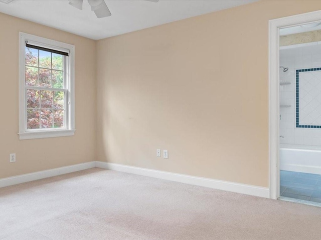 spare room featuring baseboards, light colored carpet, and a ceiling fan