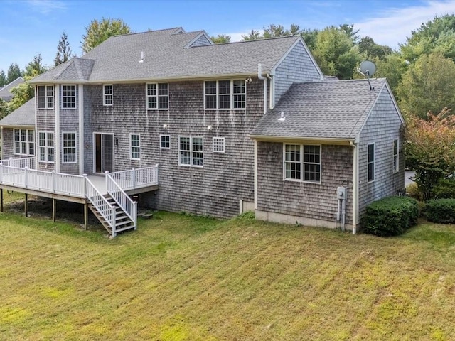 rear view of property featuring a deck, a yard, and roof with shingles