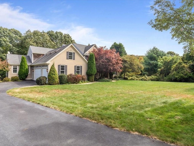 view of front of property featuring driveway, a front yard, and an attached garage