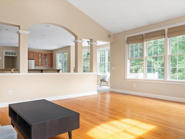 living room with baseboards, ornate columns, visible vents, vaulted ceiling, and light wood-type flooring