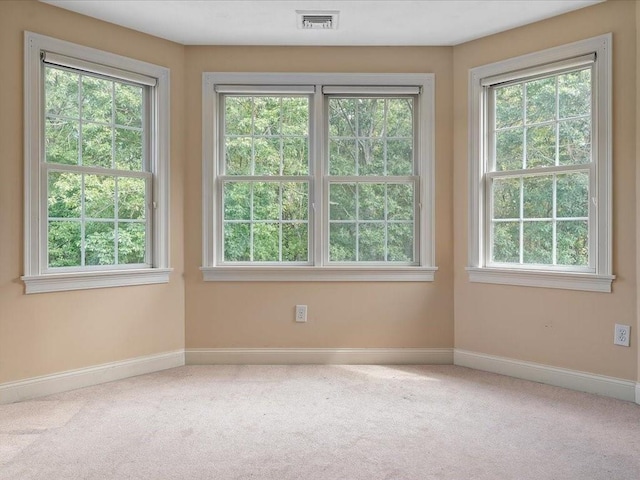 carpeted spare room with visible vents, plenty of natural light, and baseboards