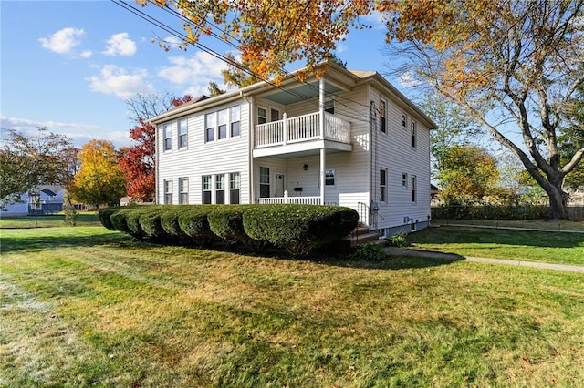 back of property with a balcony and a lawn