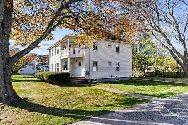 view of front of house featuring a front lawn and a balcony