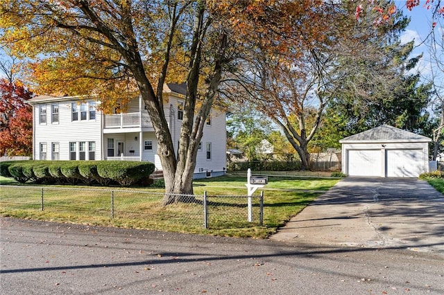 view of front facade featuring an outbuilding, a front lawn, a fenced front yard, a detached garage, and a balcony