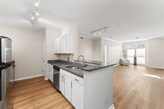 kitchen featuring dark stone countertops, appliances with stainless steel finishes, light wood-style flooring, white cabinets, and a sink