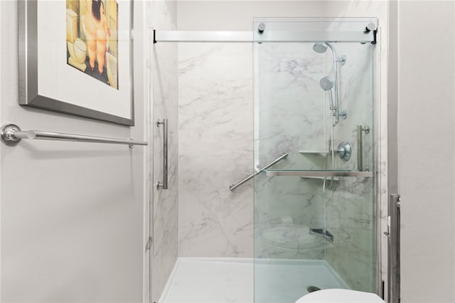 full bath with a marble finish shower and toilet