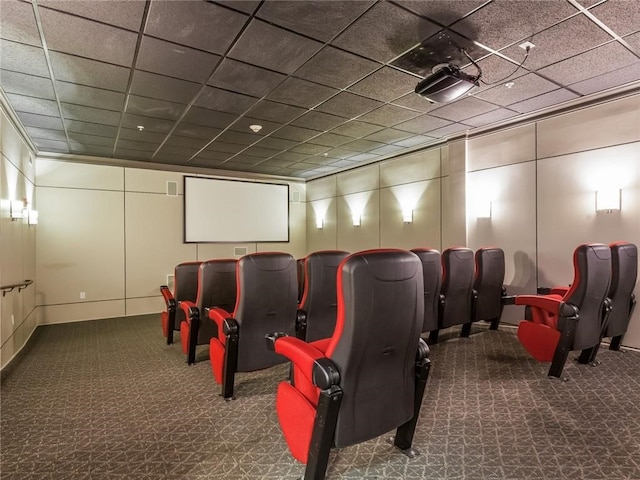 carpeted home theater with a drop ceiling and a decorative wall