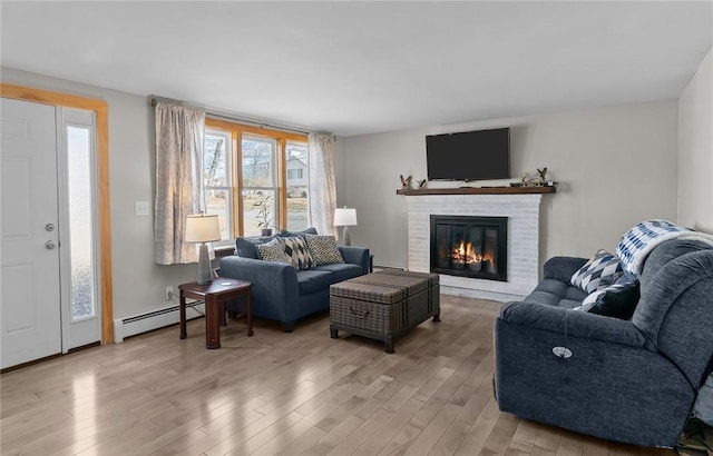 living area with a brick fireplace, a baseboard heating unit, light wood-type flooring, and a baseboard radiator