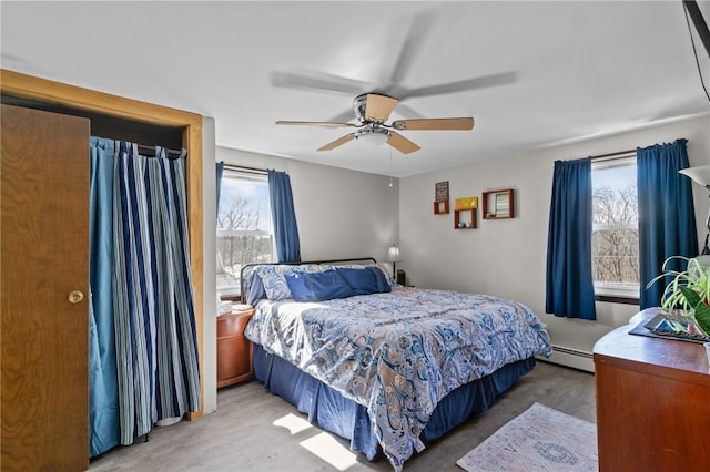 bedroom featuring a baseboard heating unit, multiple windows, light wood-style floors, and ceiling fan