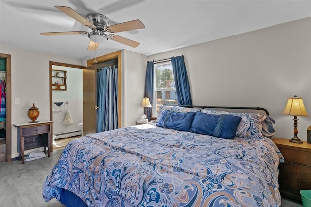 bedroom featuring wood finished floors, baseboard heating, and ceiling fan