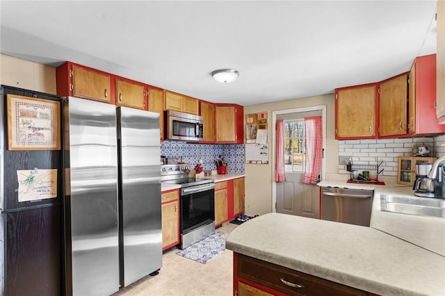 kitchen featuring decorative backsplash, appliances with stainless steel finishes, light countertops, and a sink