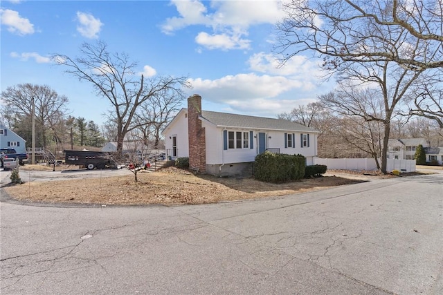 view of front of home with crawl space, a chimney, and fence